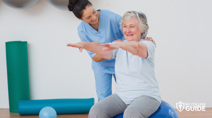 Fitness instructor conducting kinesiology exercise with an old woman