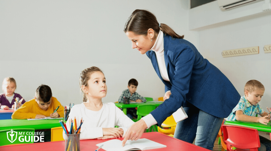 Preschool teacher guiding a student
