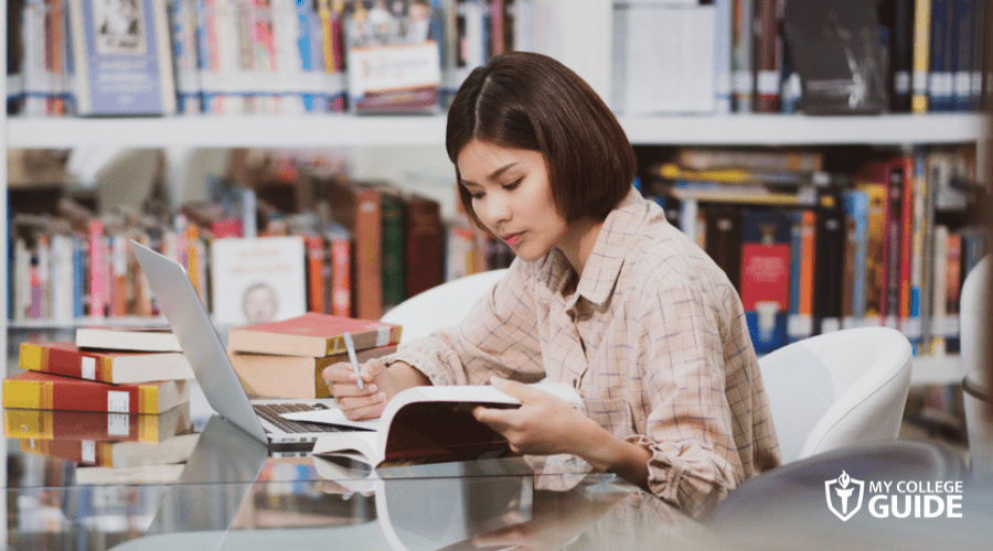 university student doing homework in library
