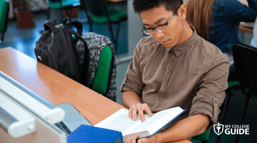 high school student reading book in library
