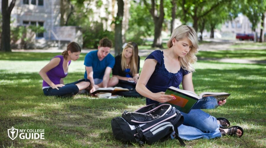 Students reading a book on the campus ground